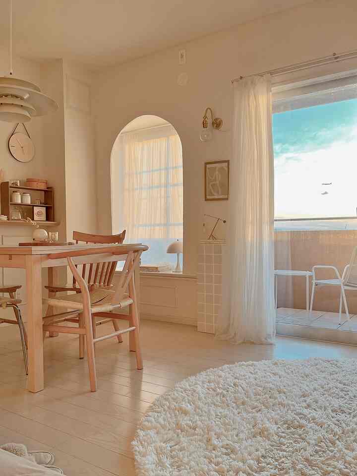 ナチュラルカラーと木目調のリビングダイニング、ラウンドラグとカーテンが配置された雰囲気のあるインテリア