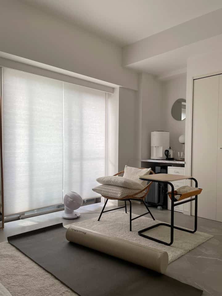 ナチュラルカラーの狭いダイニングルーム、サイドテーブルとハニカムブラインドが配置された落ち着いた空間