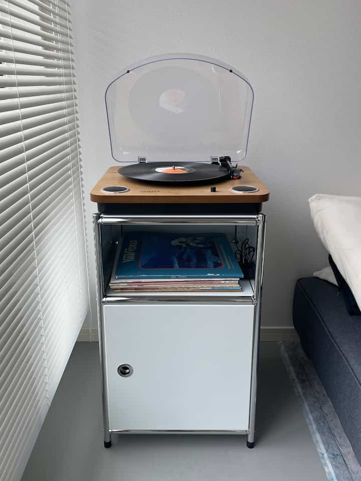 白と木目調の調和が取れたリビングのナイトテーブルにレコードプレーヤーが置かれたシンプルなインテリア