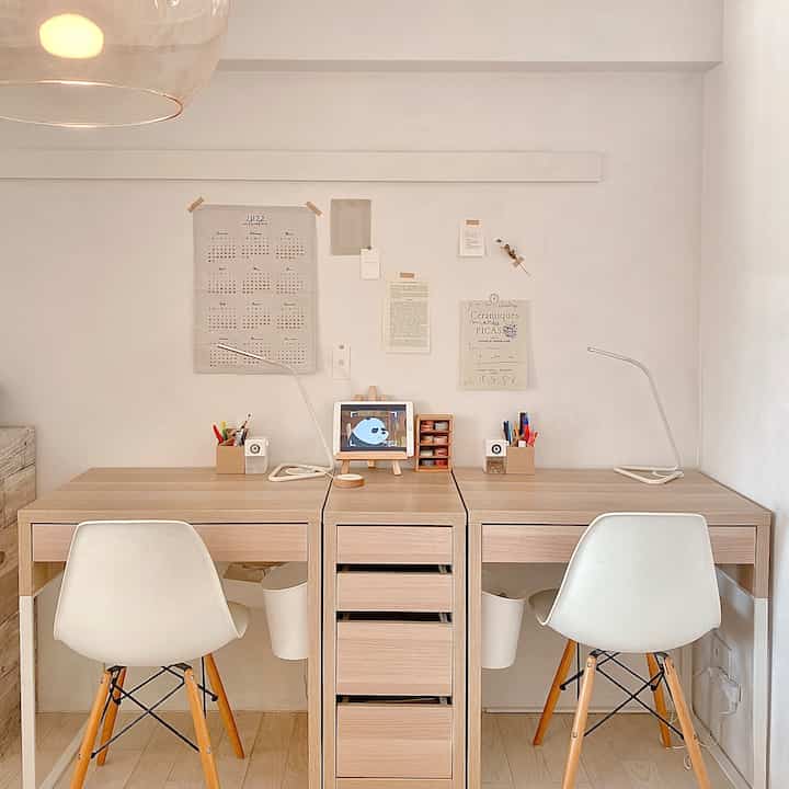 A simple natural two-person kids' room home office with white walls and wood-tone desks