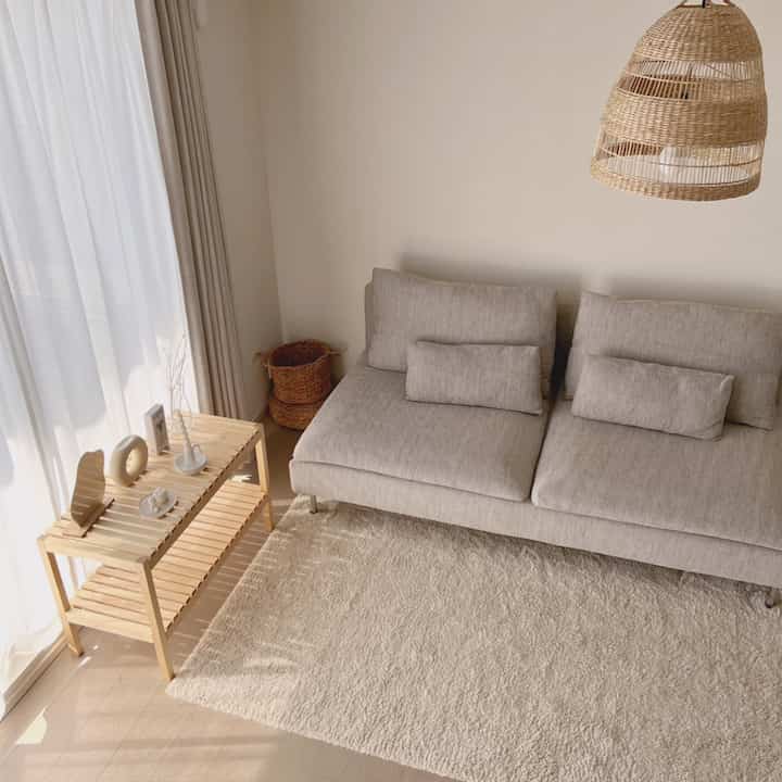 Natural beige-toned living room with gray sofa and wooden rack, creating a warm and cozy space