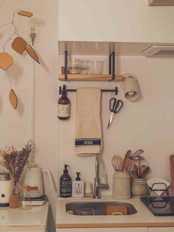 ナチュラルカラーのキッチン空間、シンクとキッチンタオル、調理器具が配置された温かみのあるインテリア