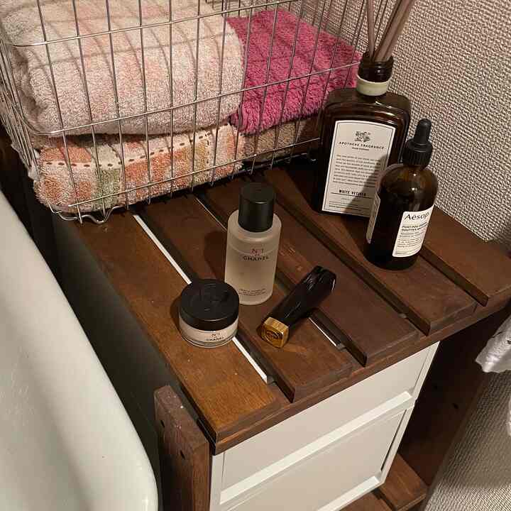 ナチュラルな木目調と白を基調とした浴室、タオルとディフューザーが配置された雰囲気のある空間