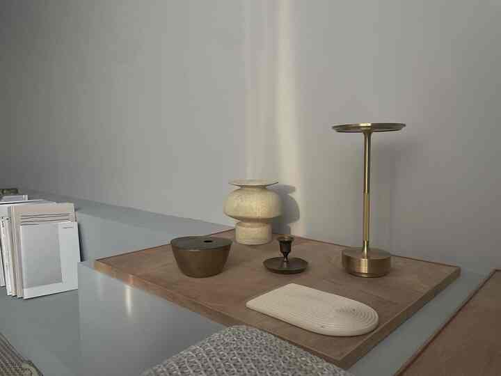 ナチュラルなブラウンの木製トレイにゴールドトーンの真鍮オブジェが配置されたシンプルなリビングのインテリア