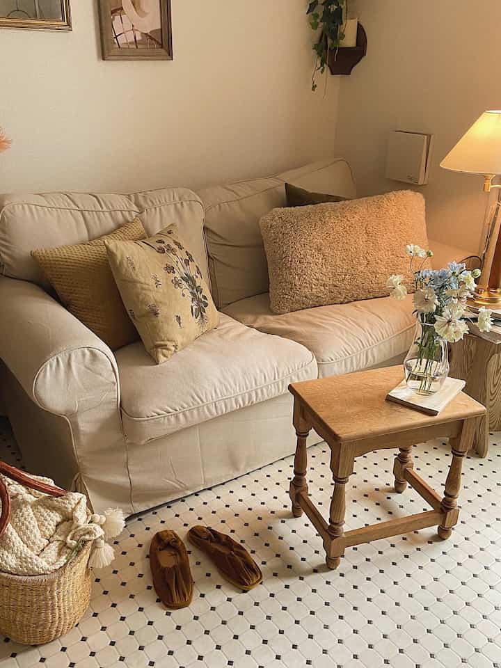 Cozy white and wood tone living room with beige cushions and a vase, featuring a simple and warm atmosphere