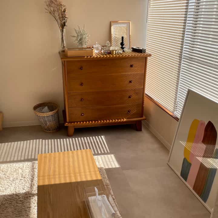 木目調とナチュラルカラーの温かみあるリビング、温かい日差しとミニマルな家具が配置された落ち着いた空間