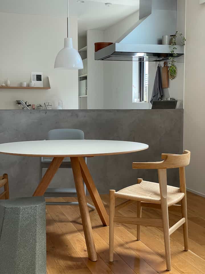 A clean kitchen and dining space blending white and wood tones, featuring a round dining table and chairs with a simple atmosphere