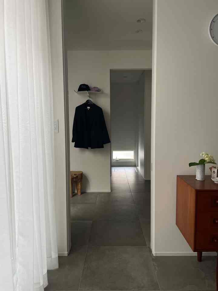 白い壁とナチュラルな木目調家具が配置された、清潔感のある玄関のインテリア