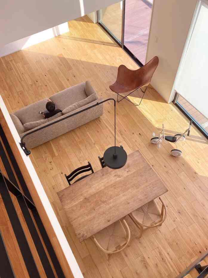 Warm natural wood tone living and dining room for a 4-person family featuring pendant lighting and child's tricycle