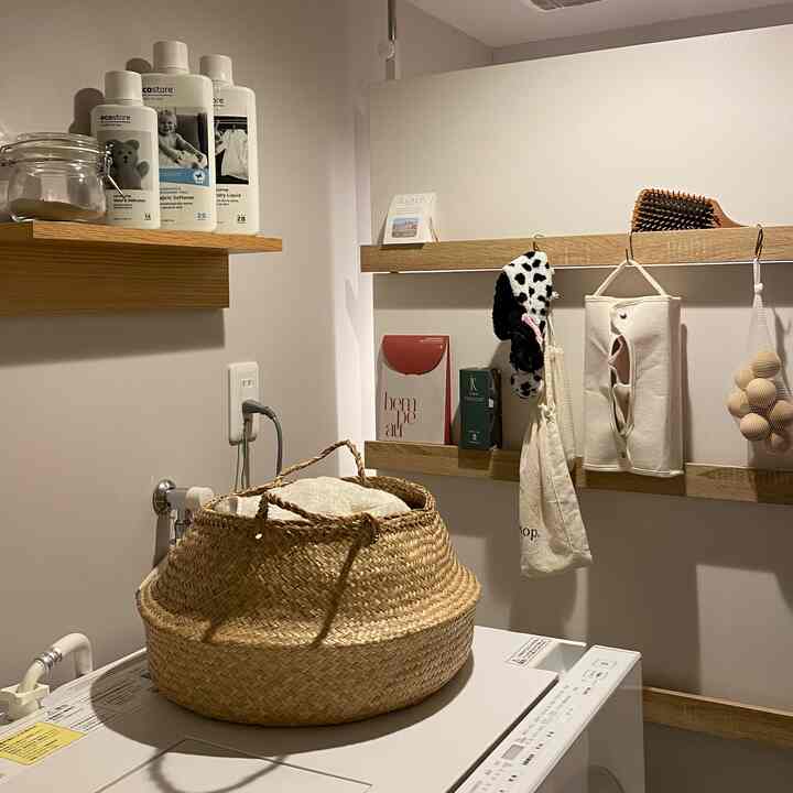 Natural tone bathroom featuring wooden wall shelves and a woven laundry basket with an organized atmosphere
