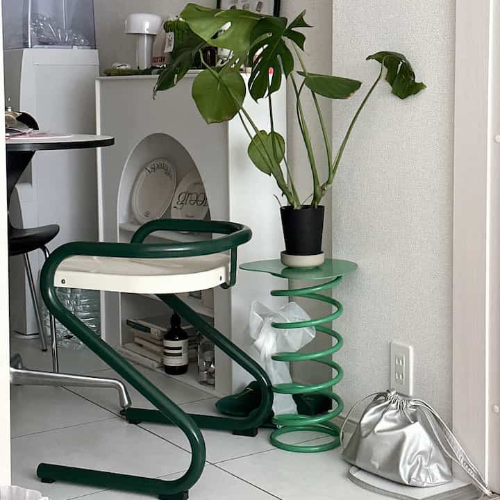 Green and white-toned Mid-Century Modern space featuring a plant and side table in a compact layout