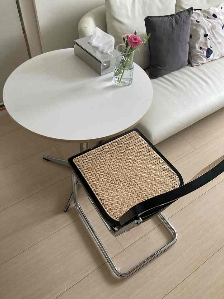 白とシルバーの色調のリビング、ラタンチェアと丸いダイニングテーブルが配置されたシンプルでモダンなインテリア