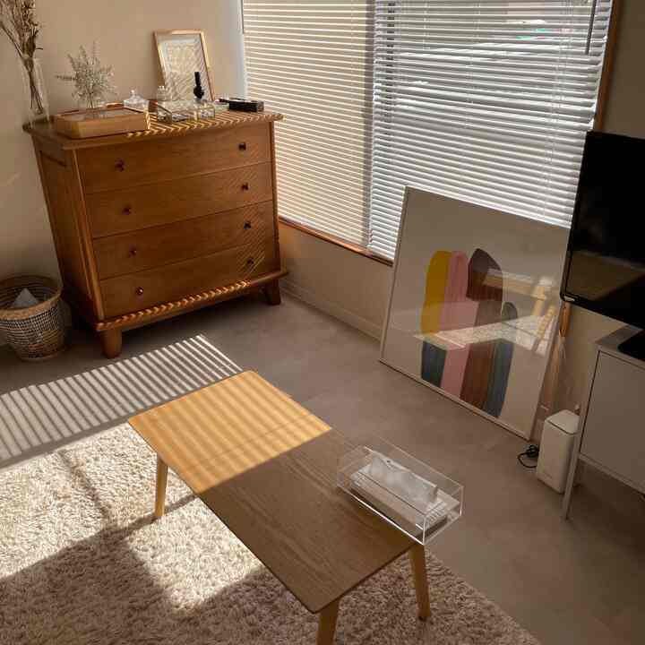 木目調と白を基調としたナチュラルなリビング、木製チェストとコーヒーテーブルが配置されたシンプルなインテリア