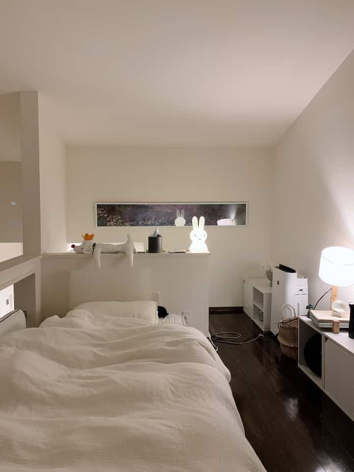 Bright white and natural toned bedroom featuring cozy bedding and soft ambient lighting creating a warm atmosphere