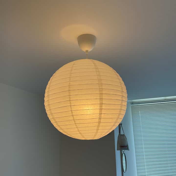 柔らかな光の丸い和紙製ペンダントライトがある白い寝室の雰囲気のあるインテリア