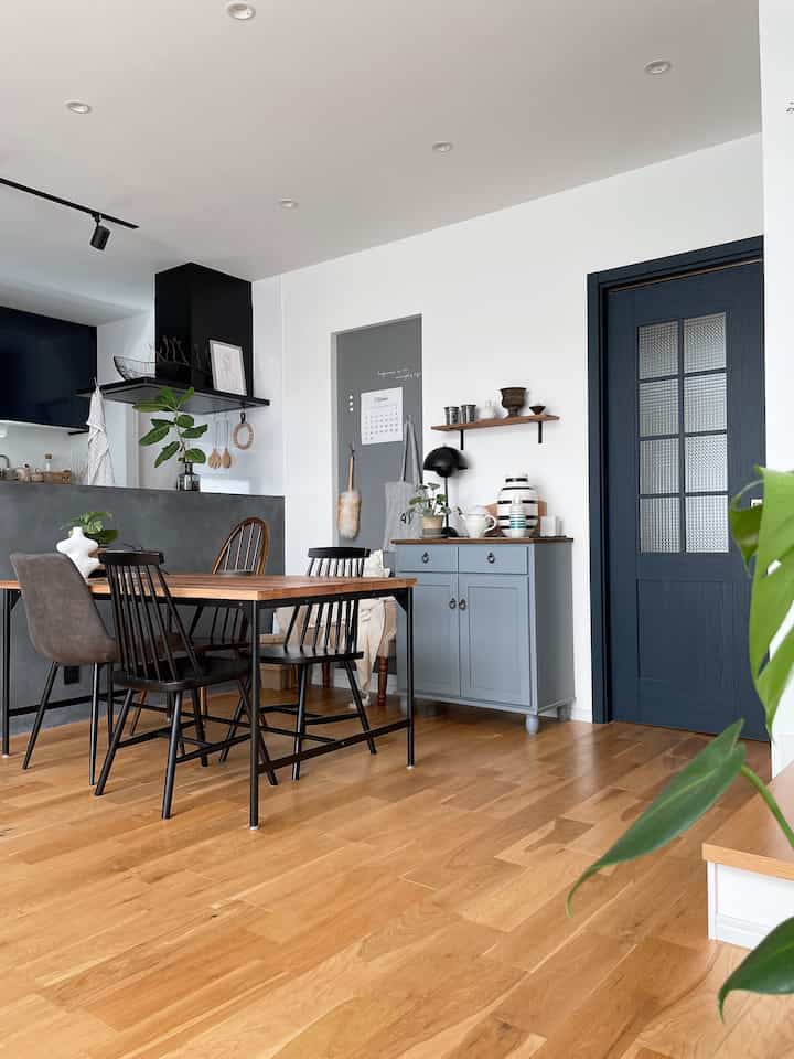 木目調の床と黒のダイニングチェアがあるナチュラルトーンのダイニングルームと青いキャビネットが調和した清潔感のある空間