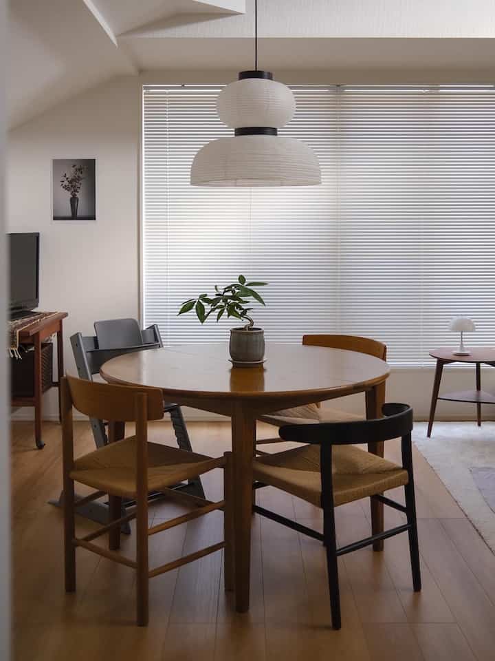 暖かい木目調と白のダイニングルーム、円形テーブルとシンプルな椅子が配置された落ち着いた空間