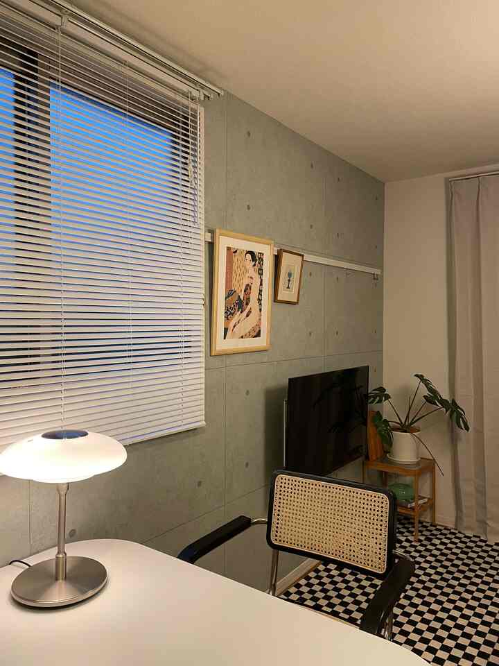 ナチュラルな色調とグレーのコンクリート壁があるダイニングルーム、木製家具とチェック柄のラグが調和した温かみのある空間