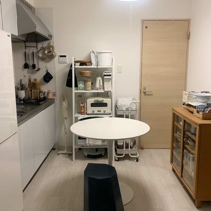 White and wood tone kitchen space featuring a round table and black stool centrally placed, creating a cozy atmosphere