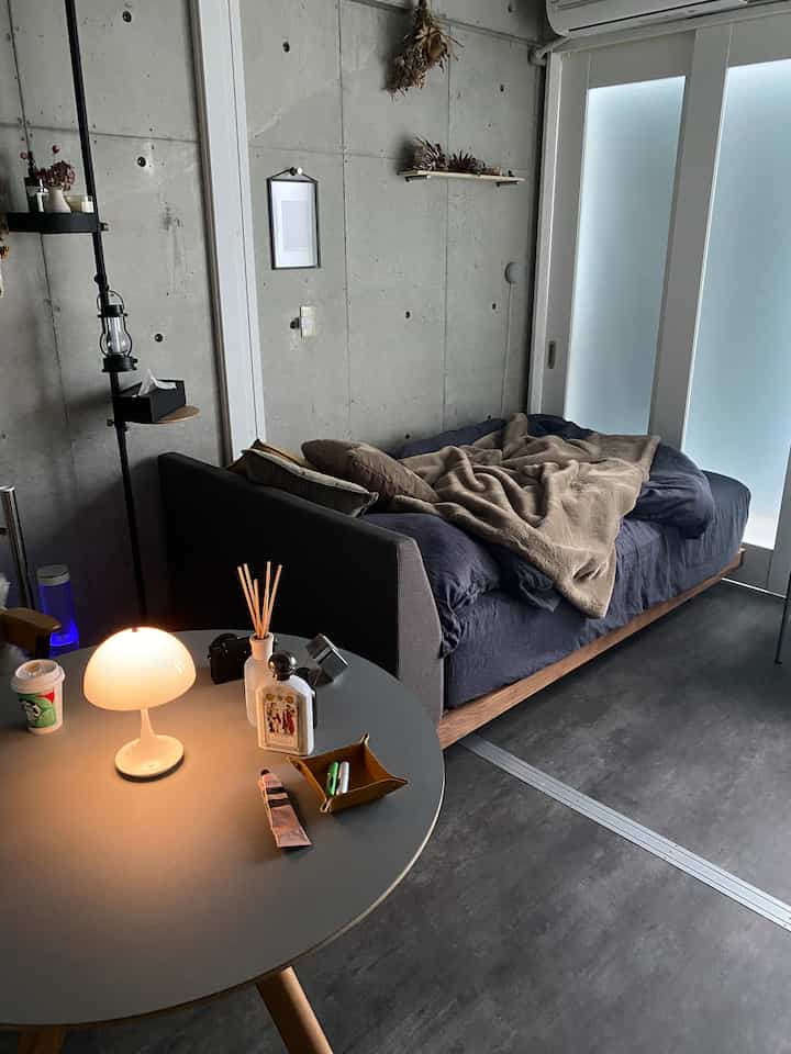 Dark gray toned modern bedroom with a sofa bed featuring brown bedding and a table lamp, creating a cozy atmosphere