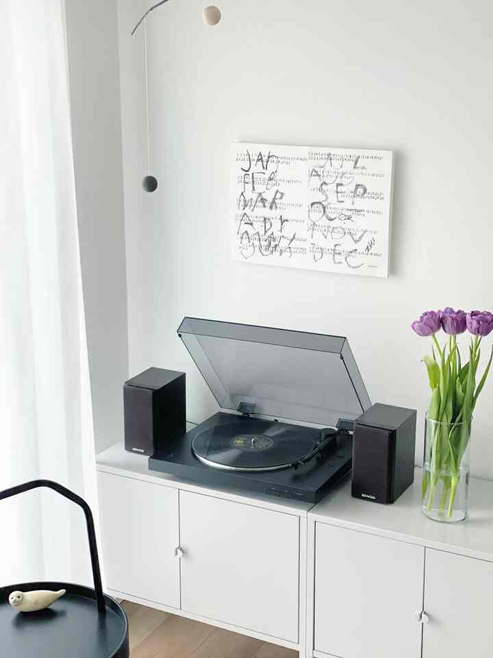 ホワイトトーンのコンパクトな書斎空間、収納キャビネット上にソニーのレコードプレーヤーとケンウッドのスピーカー、紫のチューリップの花瓶が配置された清潔感のあるインテリア
