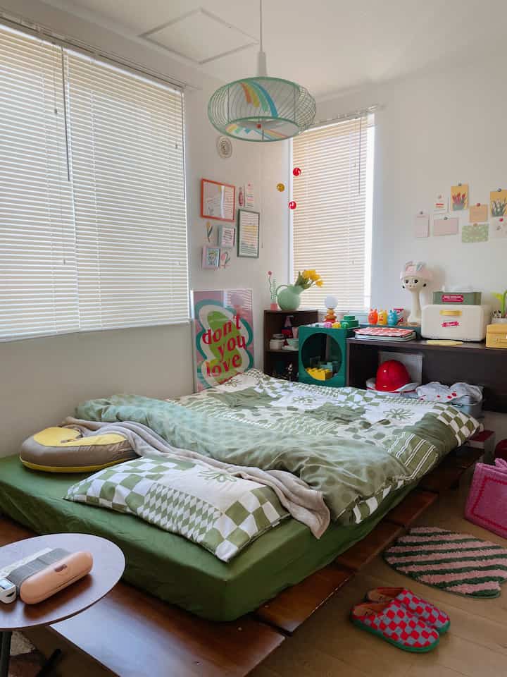 淡いグリーンの色調が印象的な寝室で、中央にパターン掛け布団カバーのベッドが配置された雰囲気のあるレトロな空間