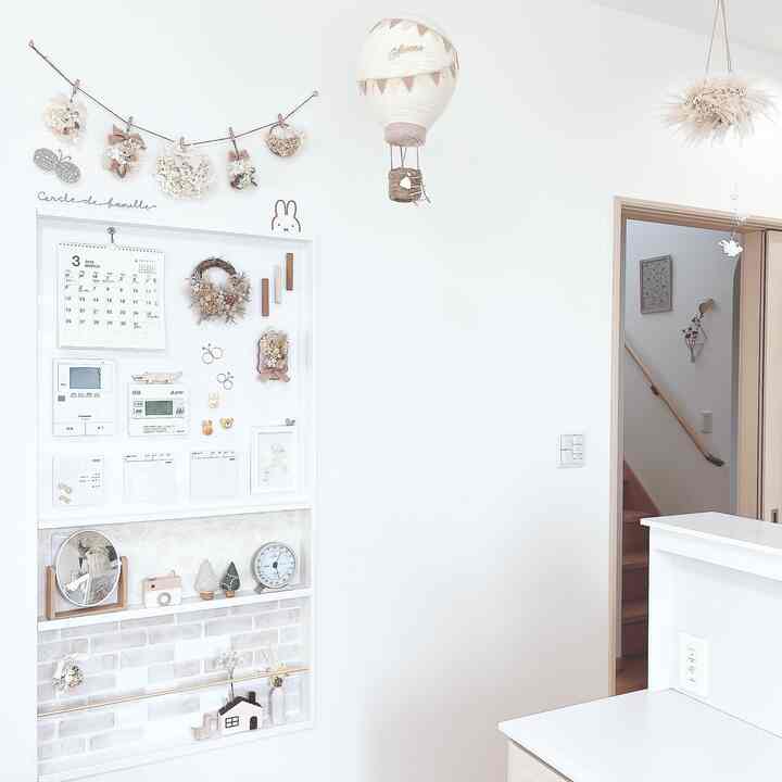白とベージュの壁があるナチュラルスタイルの空間、ホットエアバルーンのモビールと額縁が配置された清潔感のあるインテリア