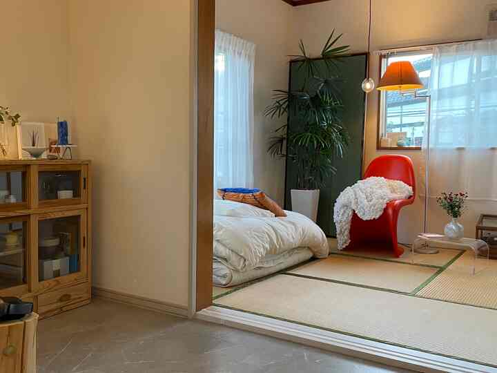 ナチュラルな色調の和室、畳の床と赤いアームチェア、フロアランプが配置された落ち着いた空間