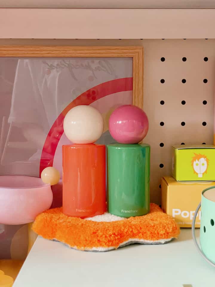 オレンジとグリーンのFrancfrancフレグランススプレーが明るい背景の棚に置かれた多彩なレトロスタイルのオブジェ