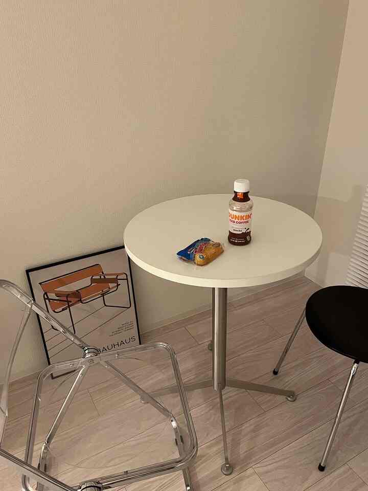 透明な椅子と白い丸テーブルが配置されたシンプルで落ち着いた小さな部屋