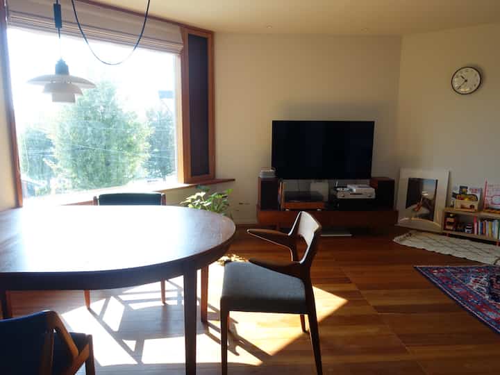 Bright living and dining area with white walls and wood-tone furniture creating a spacious natural atmosphere