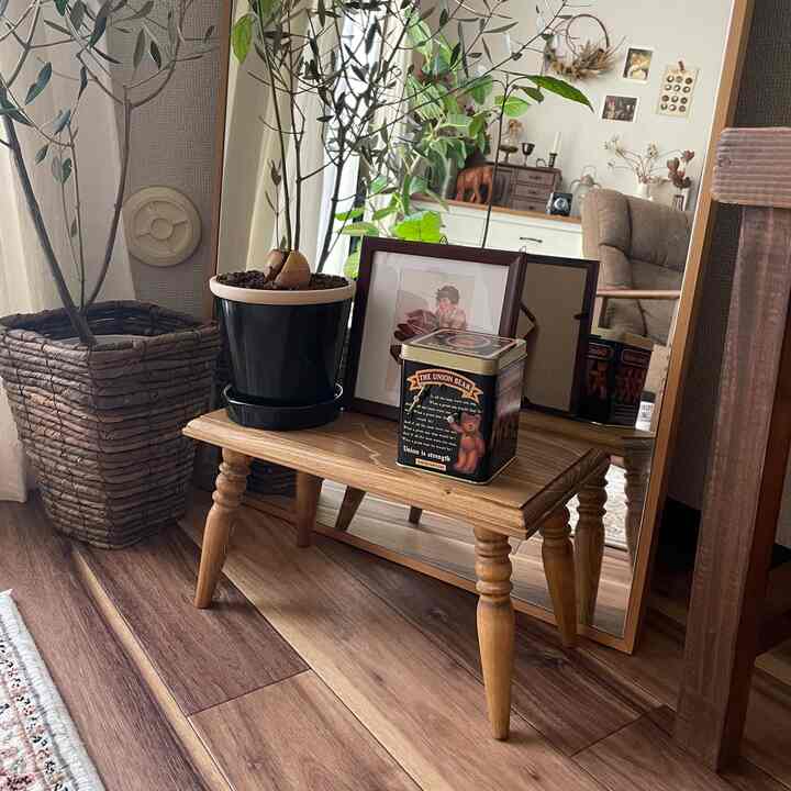 木目調の床とテーブルがある自然なコーナー収納空間、植物と鏡が配置された雰囲気のあるインテリア