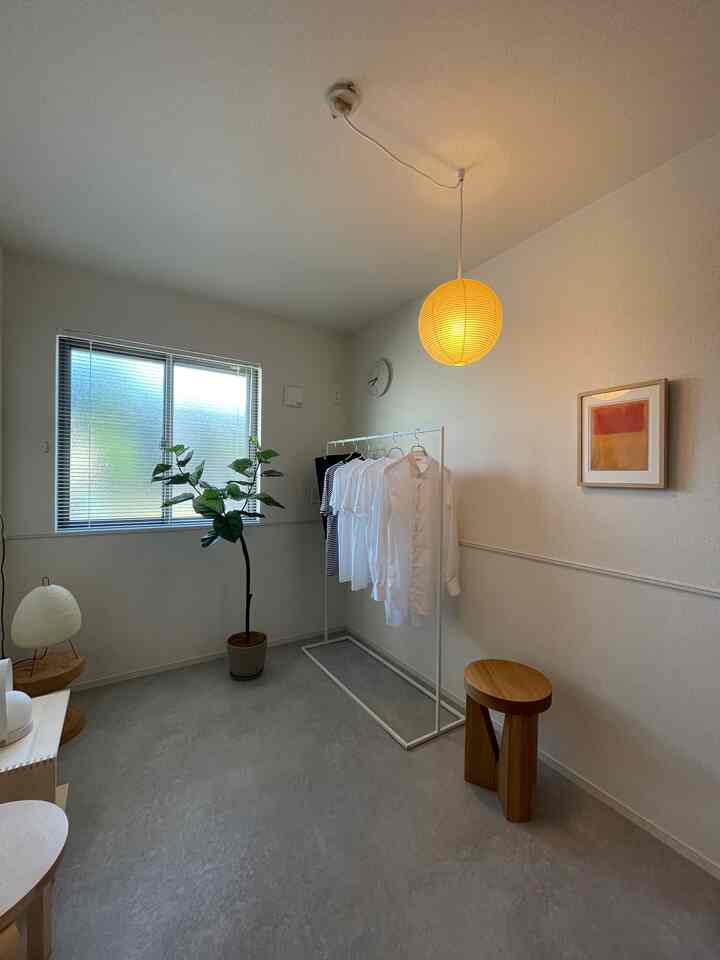 Small room with white and wood tones, featuring a window by veranda, pendant light, plant, and minimalist decor