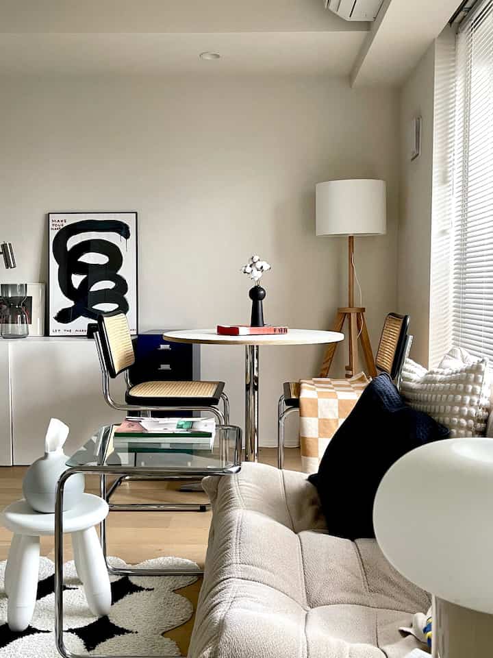 白とナチュラルウッドトーンでまとめられた二人暮らしのダイニング、ソファとフロアランプが配置された雰囲気のあるインテリア