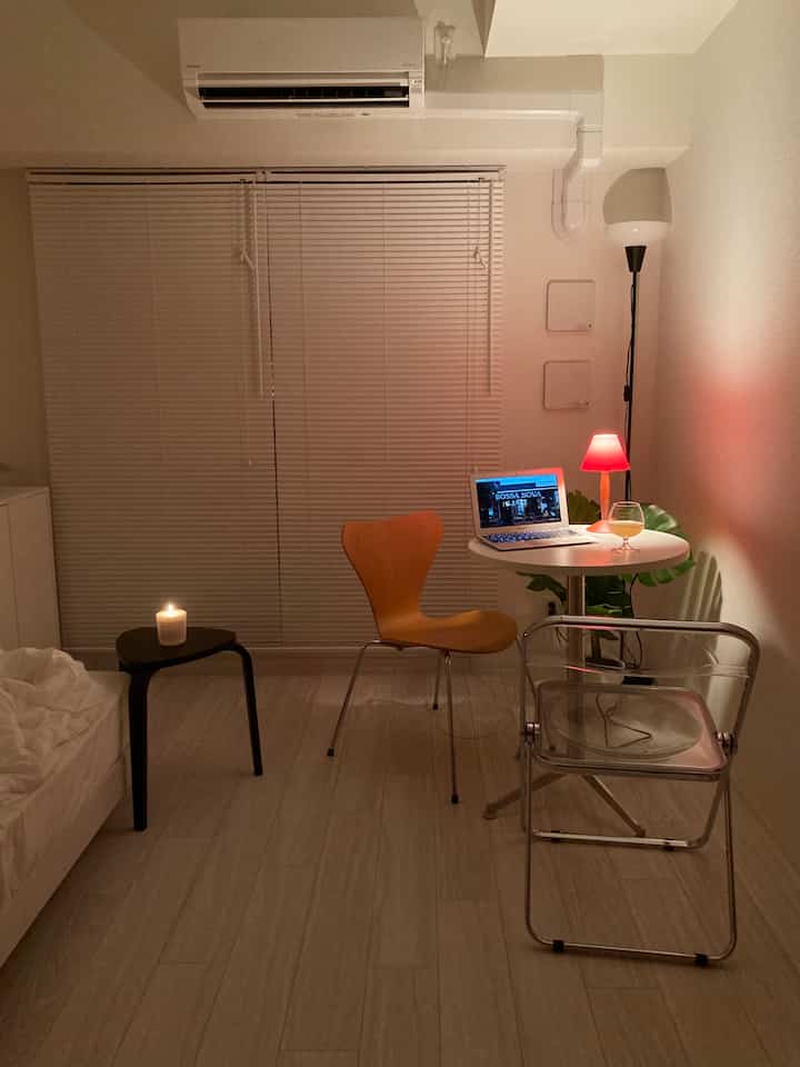 Natural and white toned small living room featuring a round table and floor lamp creating a cozy atmosphere at night