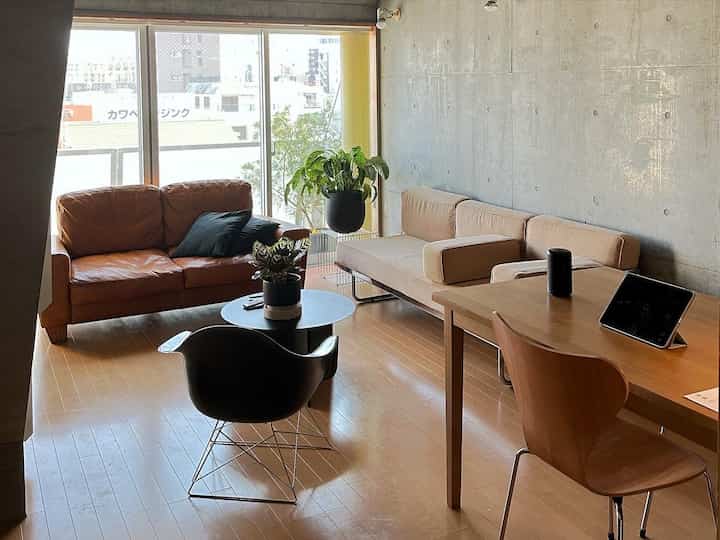 ナチュラルカラーのミッドセンチュリーモダンリビング、2つのソファと木製のダイニングテーブルが配置された温かみのあるインテリア