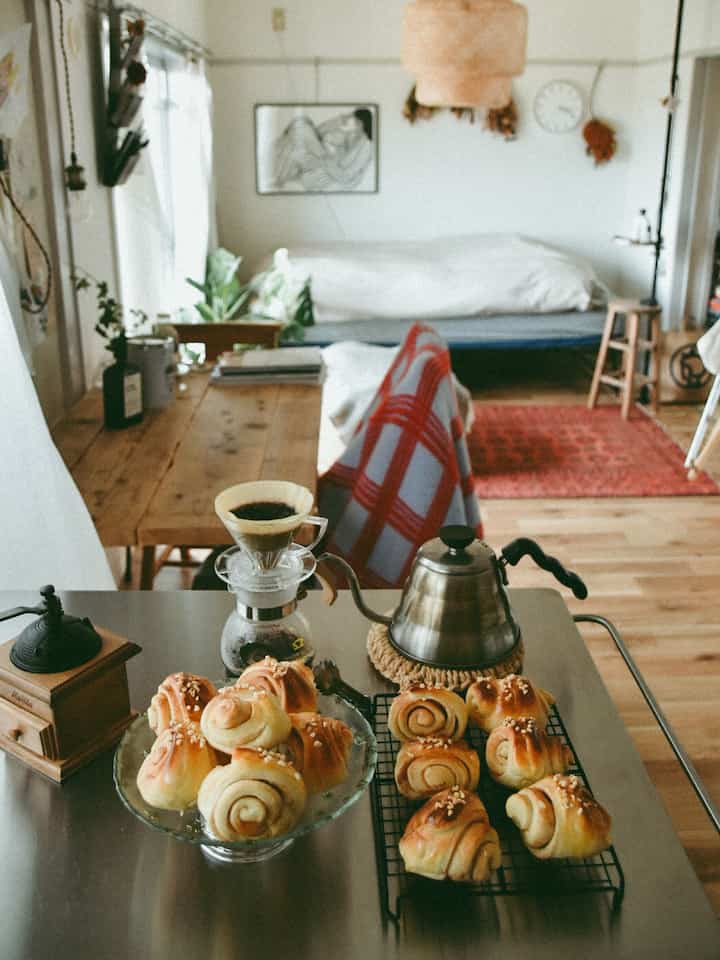 ベージュとナチュラルカラーのワンルーム、コーヒーと焼きたてのパンが置かれた雰囲気のあるおうちカフェ空間
