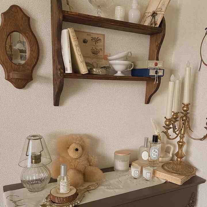 ナチュラルなブラウンの木目調とヴィンテージ風の小物が配置された、落ち着いた雰囲気のリビング。豊かなキャンドルとディフューザーが彩りを添えるインテリア。