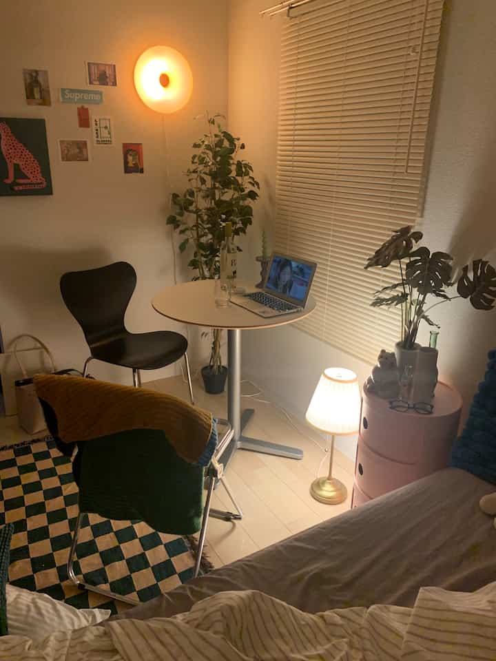 Warmly lit studio apartment living and bedroom area featuring black chair and pink storage unit with cozy ambiance