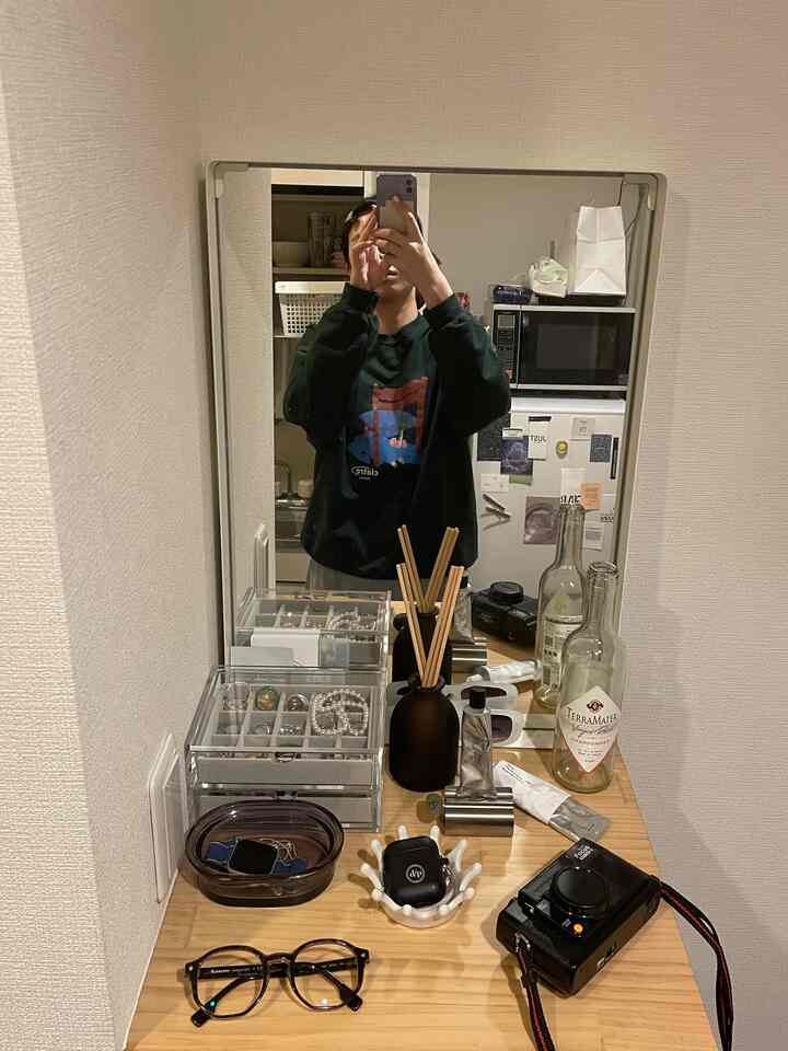 Natural wood tone entrance featuring a mirror, acrylic storage organizer, and diffuser on a clean wooden surface