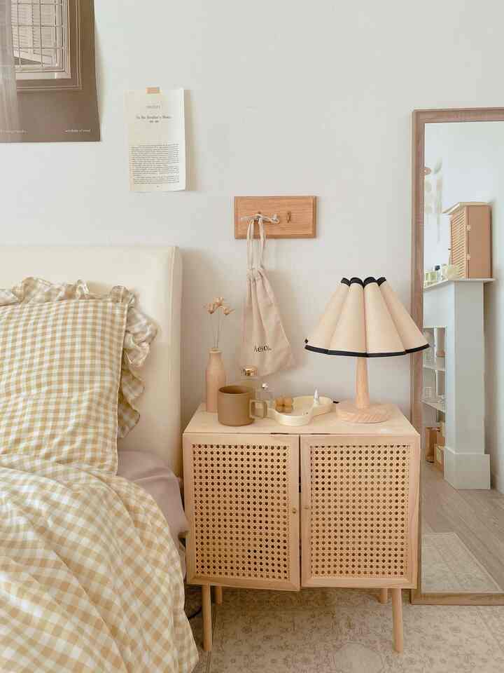 Beige and natural tone bedroom featuring a nightstand with a mug and table lamp in a cozy setting