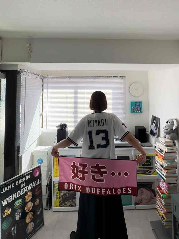 白を基調としたリビング、複数の額縁と本棚が配置されたシンプルで落ち着いたインテリア