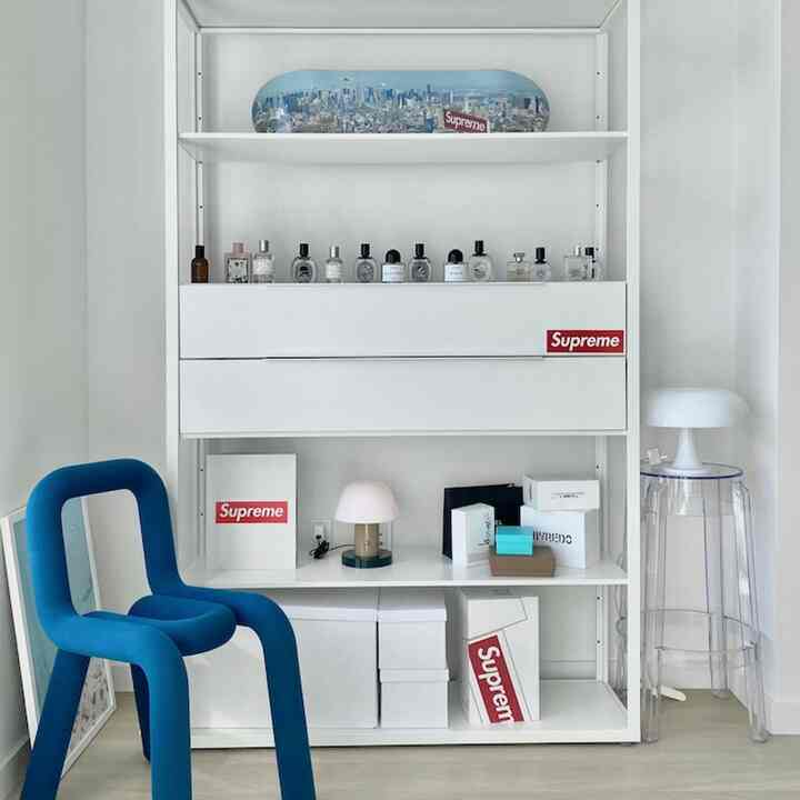 Minimalist white-toned room featuring a blue armchair and table lamp, arranged in a clean and simple interior