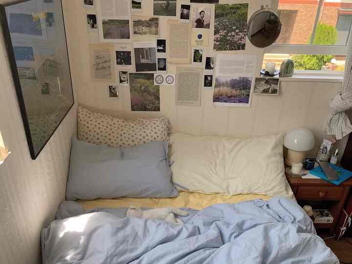 Beige and blue toned bedroom featuring a bed with nightstand and table lamp, conveying a simple atmosphere