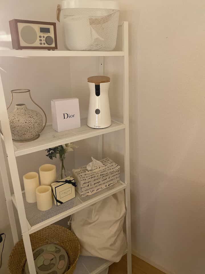 Cozy white-toned shelf space featuring organized dog supplies and a pet camera