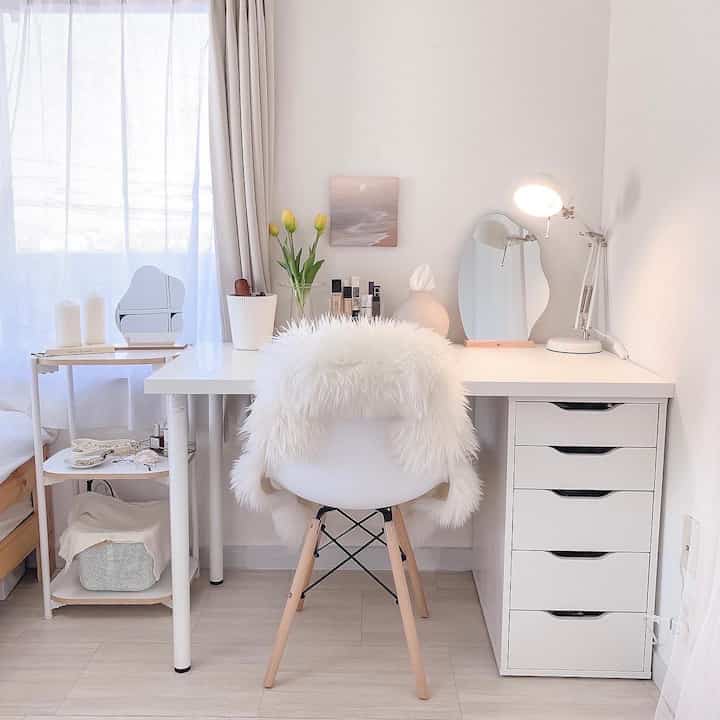 Bright white-toned home office and vanity space featuring a white desk and chair by a window with natural light
