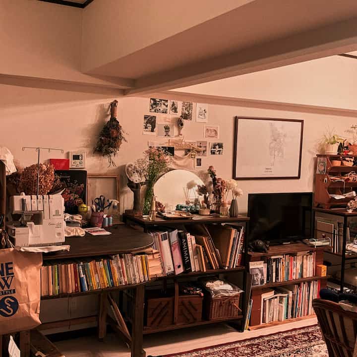 Warm beige-toned living room featuring bookshelves and desk with various personal items creating a cozy atmosphere