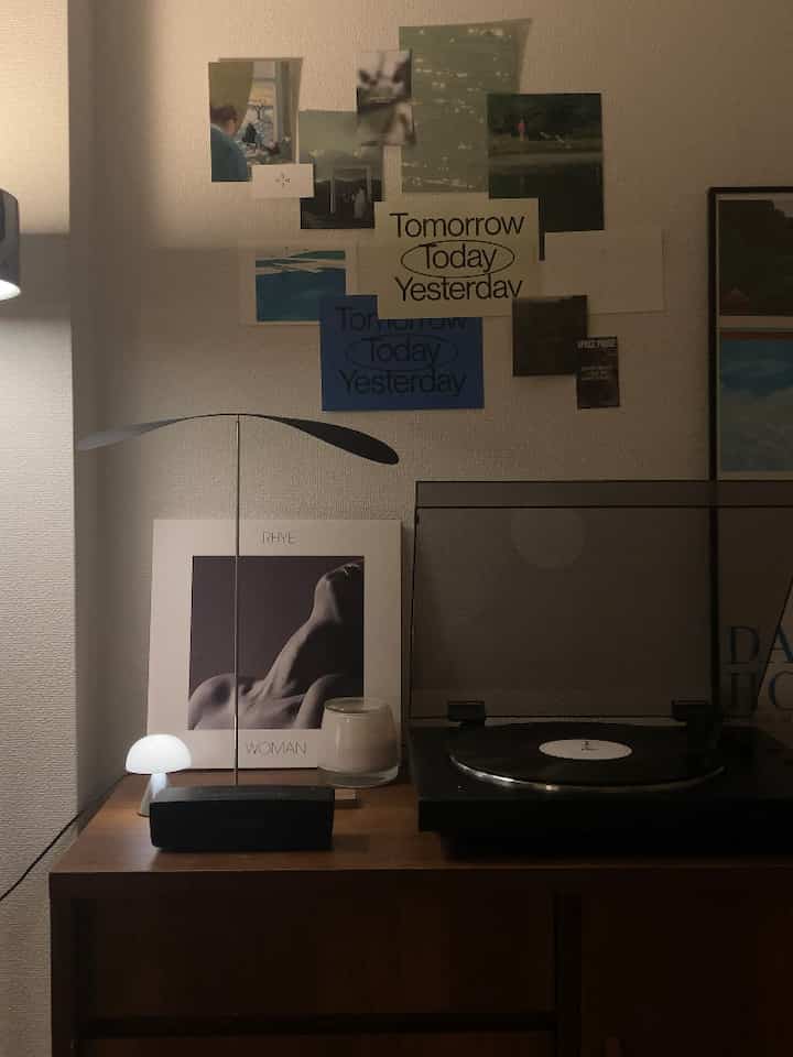 ウッドトーンとミッドセンチュリーモダン家具のある小さな部屋、LPプレーヤーとポスターが配置された雰囲気のあるインテリア