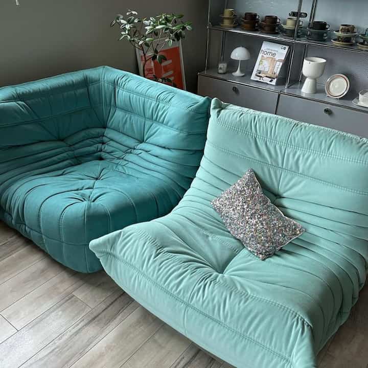 ミント色のソファが配置されたリビング、木目調の床とシンプルなインテリアが調和した雰囲気のある空間