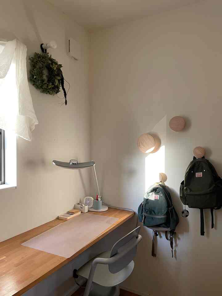 白い壁と木目調のデスクが配置された子供用の学習スペース、リュックサックと整った雰囲気のあるインテリア